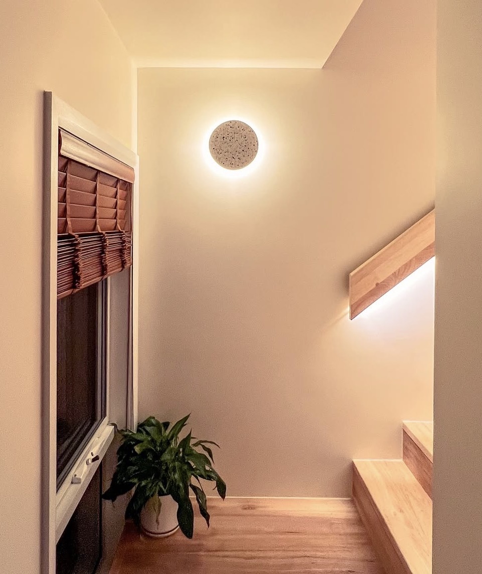 Warm stairwell detail with terrazzo sconce and timber handrail